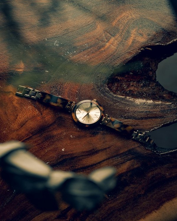 Small tortoiseshell watch on a dark wood surface